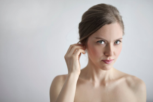 A woman holding her ear while looking into the camera.