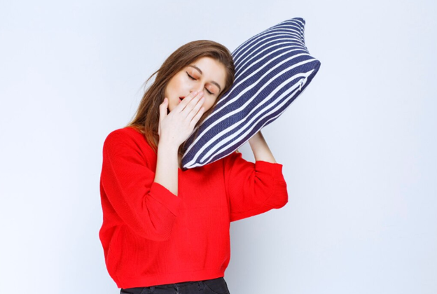 Woman Yawing and Holding a Pillow